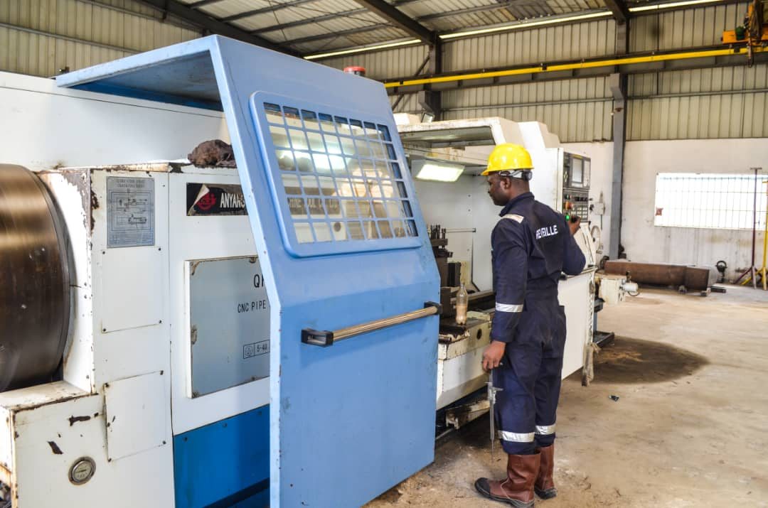 Technician at a CNC pipe threading machine control panel